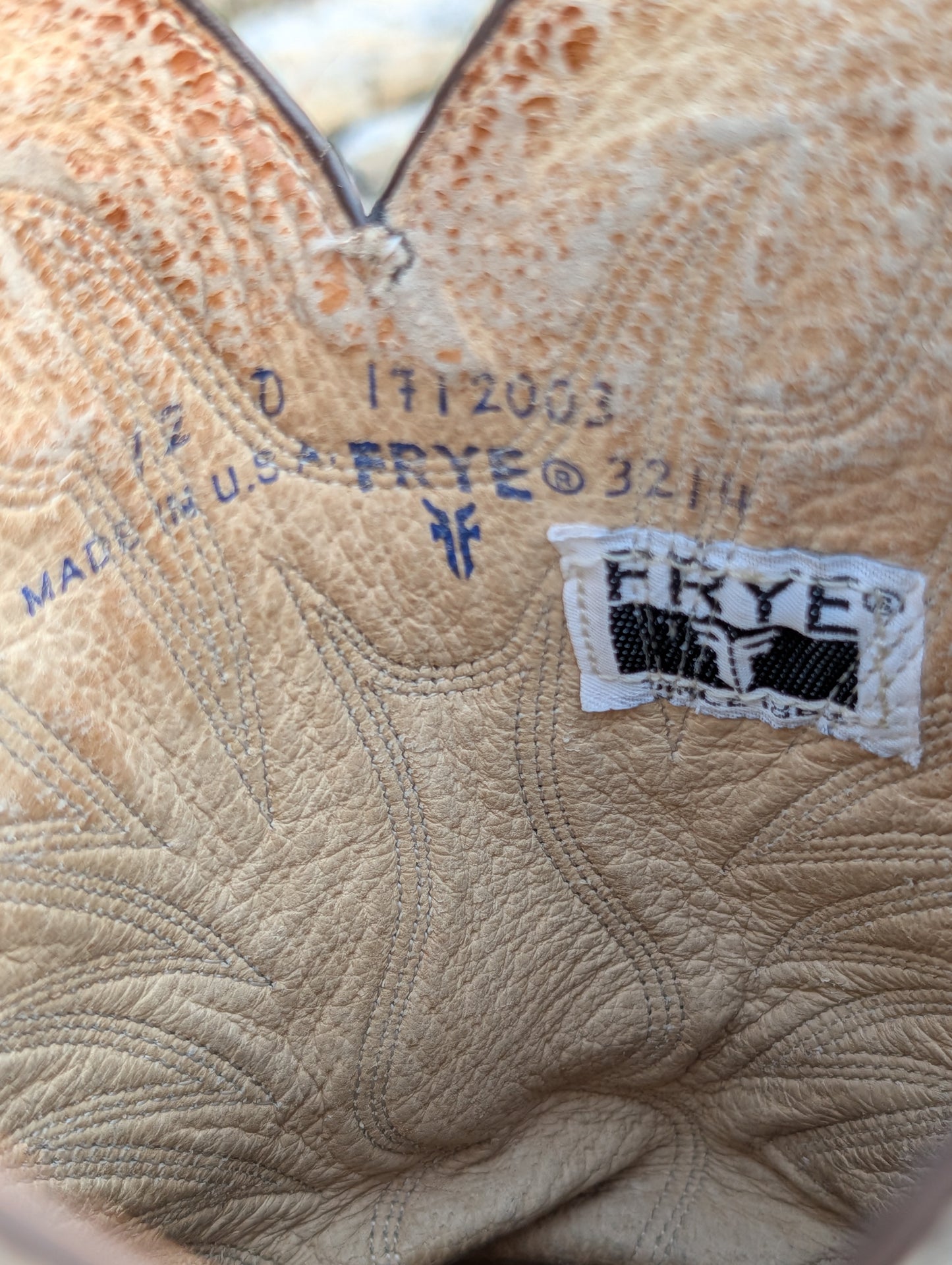 Close-up of the interior of a cowboy boot made of textured tan leather, showing stamped manufacturing details, Size 12 D, Made in USA, and a black and white brand patch reading FRYE.